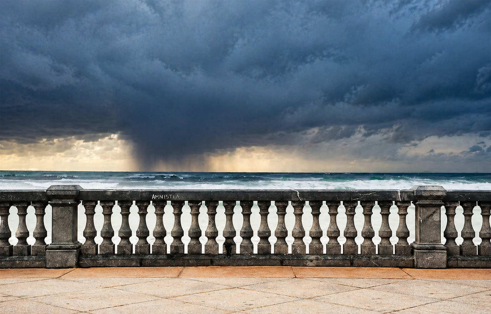 Stone seafront railing before a stormy sea